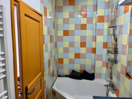 ein Badezimmer mit einer Badewanne und einer farbenfrohen Wand mit Fliesen in der Unterkunft L'interlude in Chaville