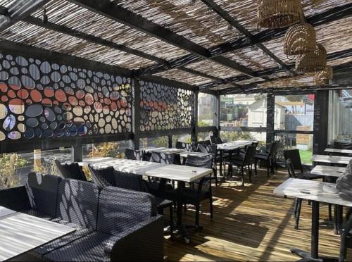 a restaurant with tables and chairs and a wall of windows at Hôtel des Pins in Jullouville-les-Pins