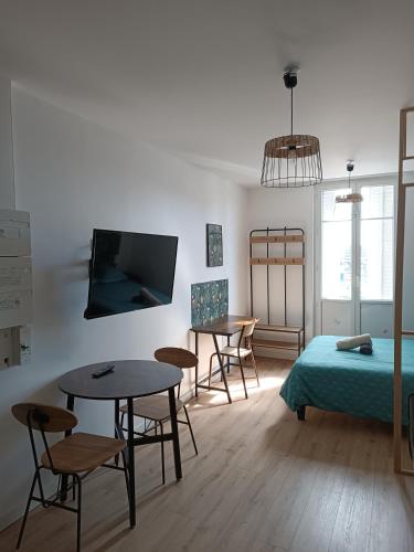 - un salon avec deux tables et un lit dans l'établissement Résidence Les Bénédictins, à Limoges