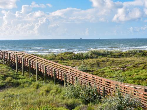a wooden boardwalk on the beach near the ocean at Tranquil Cove in Port Aransas