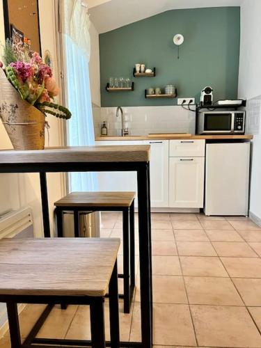 une cuisine avec une table et des chaises et un micro-ondes dans l'établissement Aix-en-Provence, Cosy Studio proche toutes commodités, linges fournis, à Aix-en-Provence