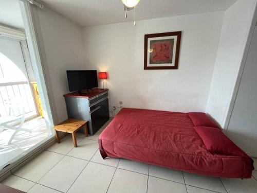 - une chambre avec un lit rouge et une télévision dans l'établissement Studio 2 pers avec terrasse et piscine au Cap d'Agde - FR-1-249A-25, au Cap d'Agde