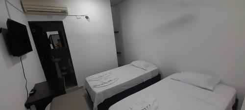 um pequeno quarto com 2 camas e um espelho em Hotel Apartado Real em Apartadó