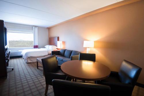 Four Points by Sheraton Winnipeg South في وينيبيغ: غرفة في الفندق مع أريكة وسرير وطاولة