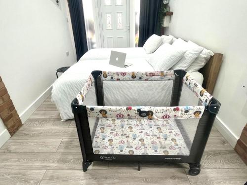 a bed with a crib with a laptop on it at Nice and Cosy Large Studio near Luton Airport in Luton