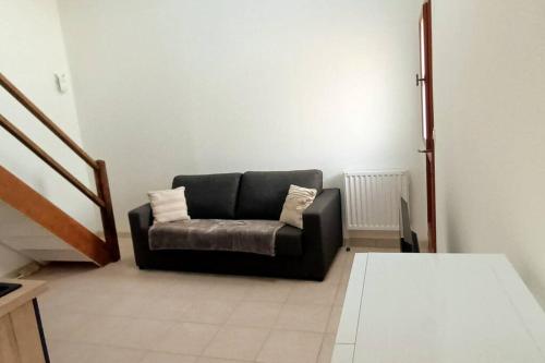 eine schwarze Couch im Wohnzimmer in der Unterkunft La Tranquillité in Laroche-Saint-Cydroine