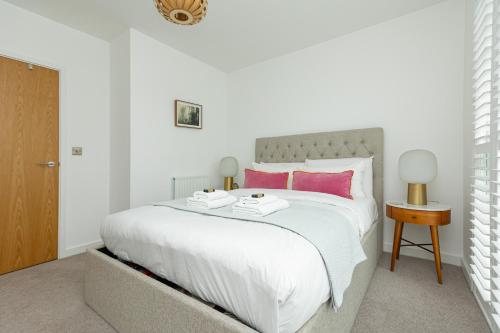 a bedroom with a large white bed with pink pillows at Stunning 1BR Flat in Hackney, 2 min London Fields in London