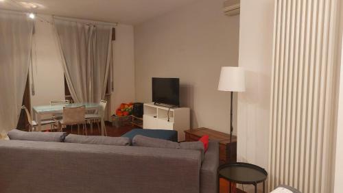 ein Wohnzimmer mit einem Sofa, einem TV und einem Tisch in der Unterkunft Appartamento Casa Verona in Verona