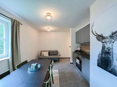 a kitchen and a living room with a table with a deer on the wall at Das Hirscherl - Mountain Design Studio in Bad Kleinkirchheim