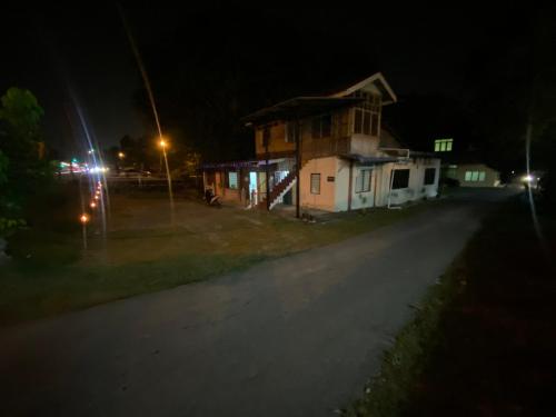 une maison sur le côté d'une route la nuit dans l'établissement Homestay Bukit Awi, à Kulim