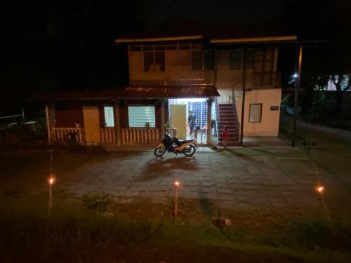 une moto garée devant une maison la nuit dans l'établissement Homestay Bukit Awi, à Kulim