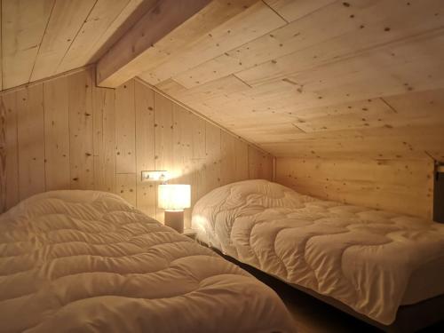 two beds in a room with wooden walls at Aux Buis Gourmands in La Chapelle-en-Vercors