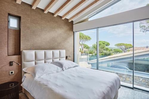 une chambre avec un grand lit et une grande fenêtre dans l'établissement Villa Calanque, Saint-Tropez, à Saint-Tropez