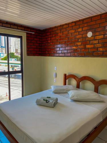 a bedroom with a large white bed with a brick wall at Felicità Praia Hotel in Fortaleza