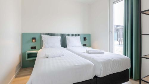 ein großes weißes Bett in einem Zimmer mit Fenster in der Unterkunft Molecaten Park Waterdunen in Breskens