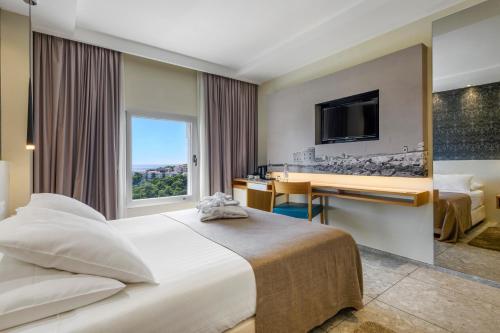 ドゥブロヴニクにあるホテル レロのベッド、デスク、テレビが備わるホテルルームです。