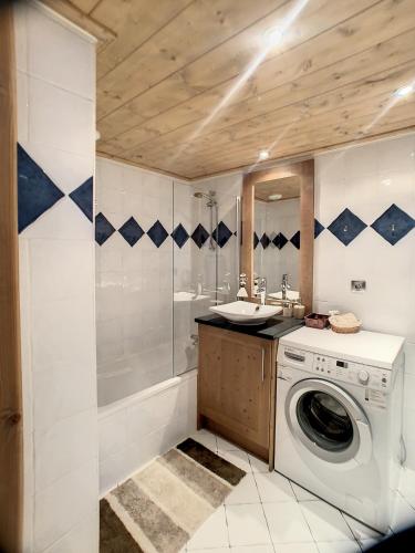 une salle de bain avec une machine à laver et un lavabo dans l'établissement rous 03, aux Carroz d'Arâches