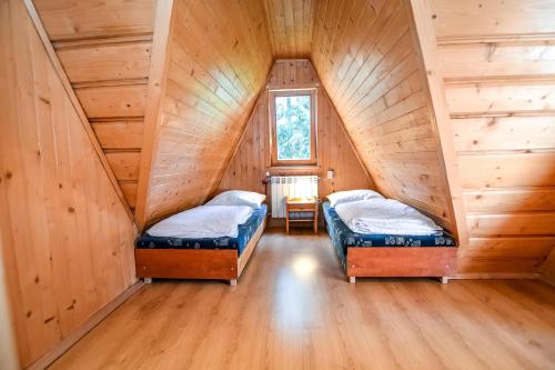 two beds in a attic room with wooden walls at Wspólna Chata in Białka Tatrzańska