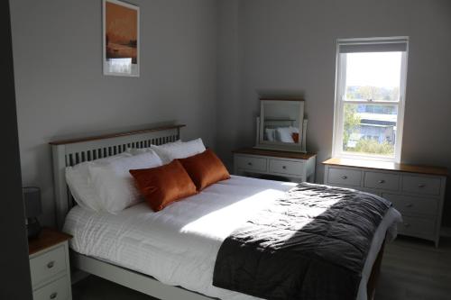 a bedroom with a bed with white sheets and orange pillows at Church Suites Enniskillen in Enniskillen