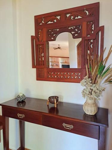 a wooden table with a mirror and a vase with flowers at Wonderful Villa Felice in Yogyakarta