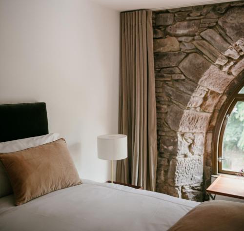 a bedroom with a bed and a stone wall at The Church Tower in Crieff