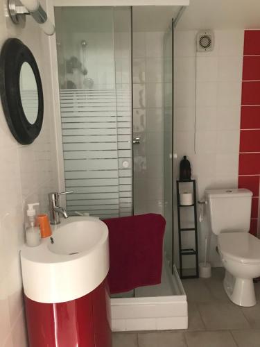 La salle de bains est pourvue d'un lavabo rouge et blanc et de toilettes. dans l'établissement Chambre indépendante privée avec salle de bain, à La Chapelle-dʼAngillon