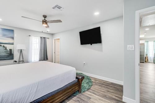 a white bedroom with a bed and a flat screen tv at Ideal Time in Padre Island