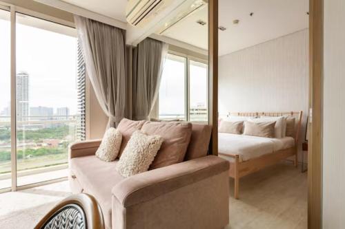 een slaapkamer met een bank en een bed met een spiegel bij Family Suite Sea view 2Bedroom at Veranda Residence Pattaya in Na Jomtien