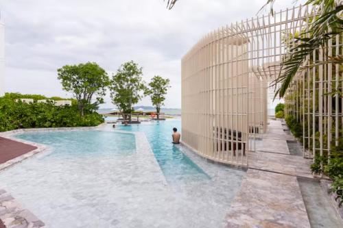 a man standing in a swimming pool next to a building at Family Suite Sea view 2Bedroom at Veranda Residence Pattaya in Na Jomtien