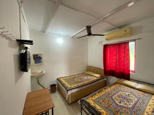 a room with two beds and a window with red curtains at Aviraj Nivas in Dapoli