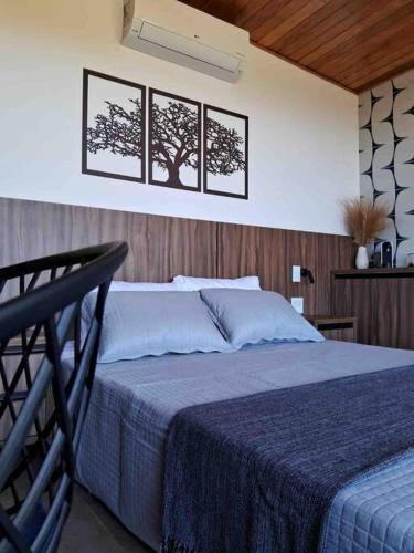 1 dormitorio con 1 cama con 3 cuadros en la pared en Casa Vértize, uma casa de alto padrão com Spa Hidro e vista espetacular en Cavalcante