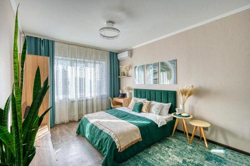 a bedroom with a green bed and a plant at Green Boutique - квартира в изумрудных оттенках на Мынбаева in Almaty