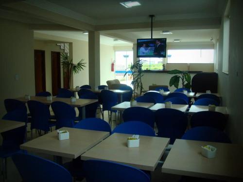 Habitación con mesas, sillas azules y TV. en HOTEL TOPAZIO, en Cristalina
