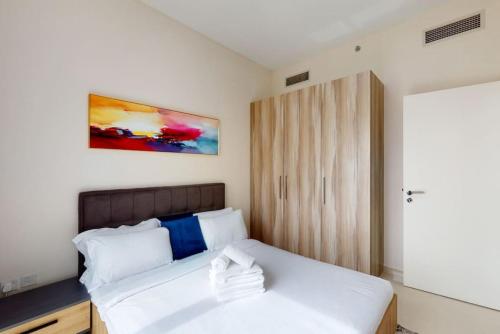 a bedroom with a white bed and a wooden cabinet at Key View - Golf Vita in Dubai Marina