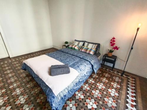 By Urquinaona Rooms في برشلونة: غرفة نوم بسرير وبطانية زرقاء وبيضاء