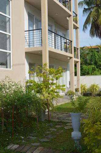 een wit appartementencomplex met een tuin ervoor bij Silina Airport Residence in Katunayaka