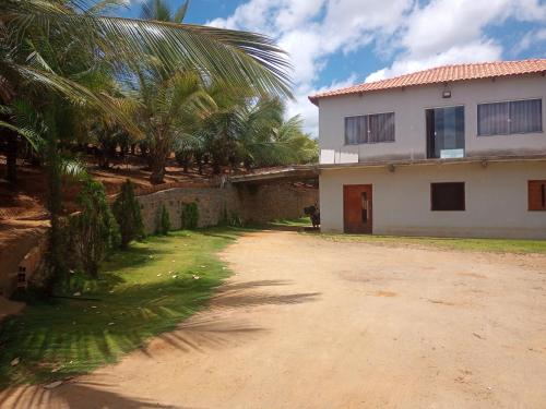 a dirt road next to a house with palm trees at Pousada e recanto baiano's in Amargosa