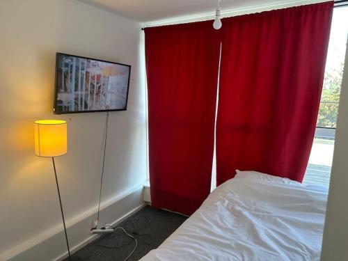 ein Schlafzimmer mit einem roten Vorhang und einem Bett neben einem Fenster in der Unterkunft 3bed Rooms Apartment Terrace in Crystal Palace