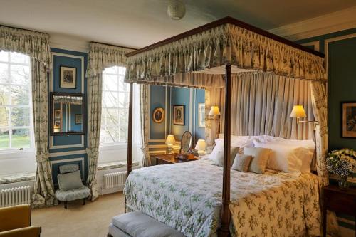 a bedroom with a canopy bed and a chair at Blyth Hall in Coleshill