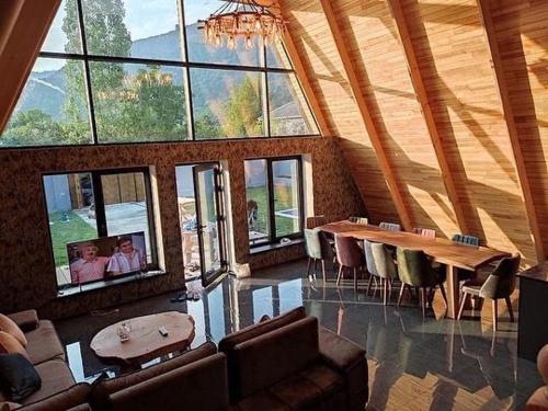 a large room with a table and chairs and windows at Qafqaz Eminent Chalet in Gabala