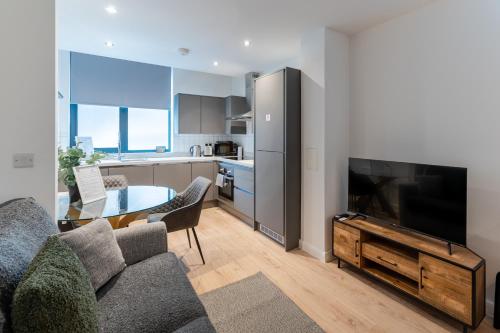 a living room with a couch and a tv and a kitchen at 123 Queen Street - Home Crowd Luxury Apartments in Sheffield