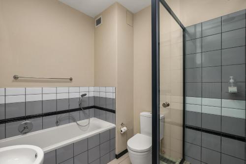 a bathroom with a tub and a toilet and a sink at Easy Stay - The Vantage Rosebank in Johannesburg