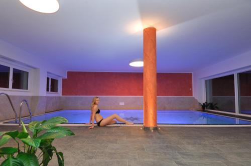 a woman is sitting in a swimming pool at Residence Viktoria in Castelrotto