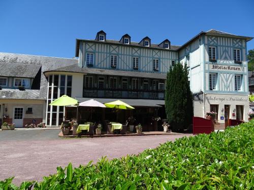 un gran edificio con mesas y sombrillas delante en Logis L'auberge Du President, en Cormeilles