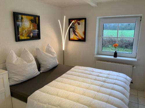 a bedroom with a white bed and a window at Ferienhaus Alte Mühle in Stoltebüll