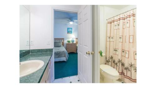 a bathroom with a toilet and a sink and a bedroom at Orlando Mouse Manor in Davenport