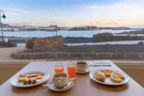 stół z dwoma talerzami jedzenia i dwoma filiżankami kawy w obiekcie Apartamentos Galeon Playa w Costa Teguise