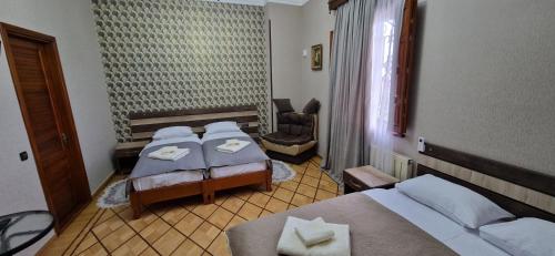 a hotel room with two beds and a chair at Hotel Villa in Kutaisi