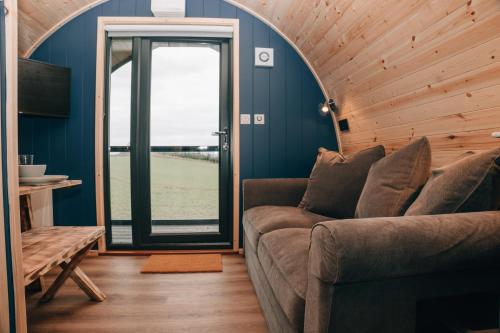 a living room with a couch and a glass door at Eastfield Glamping Farm in Spennithorne