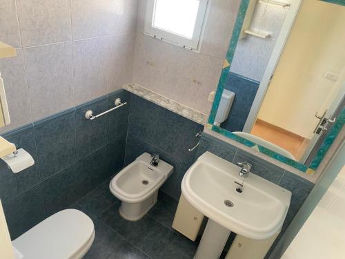 een badkamer met een wastafel, een toilet en een spiegel bij Estrella Blanca VI, 2 dormitorios, by Bookindenia in Denia